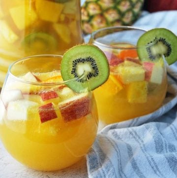 Two glasses of tropical sangria with a pitcher and pineapple in the background