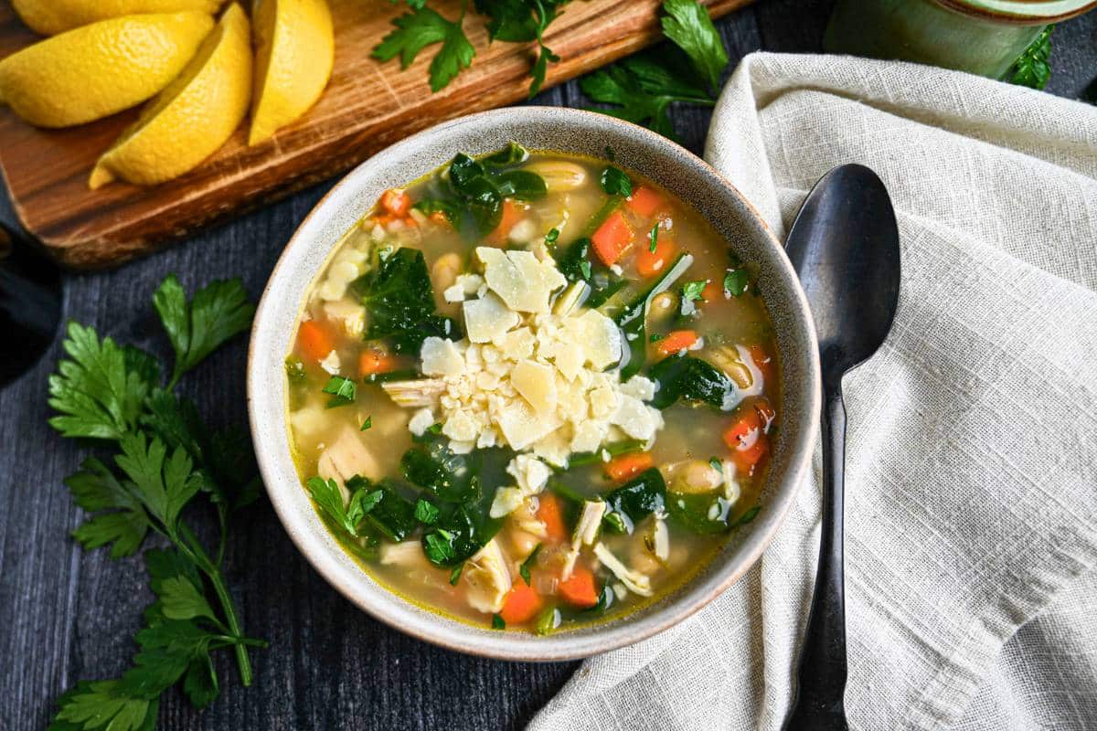 a bowl of white bean chicken soup with spinach and cheese on top
