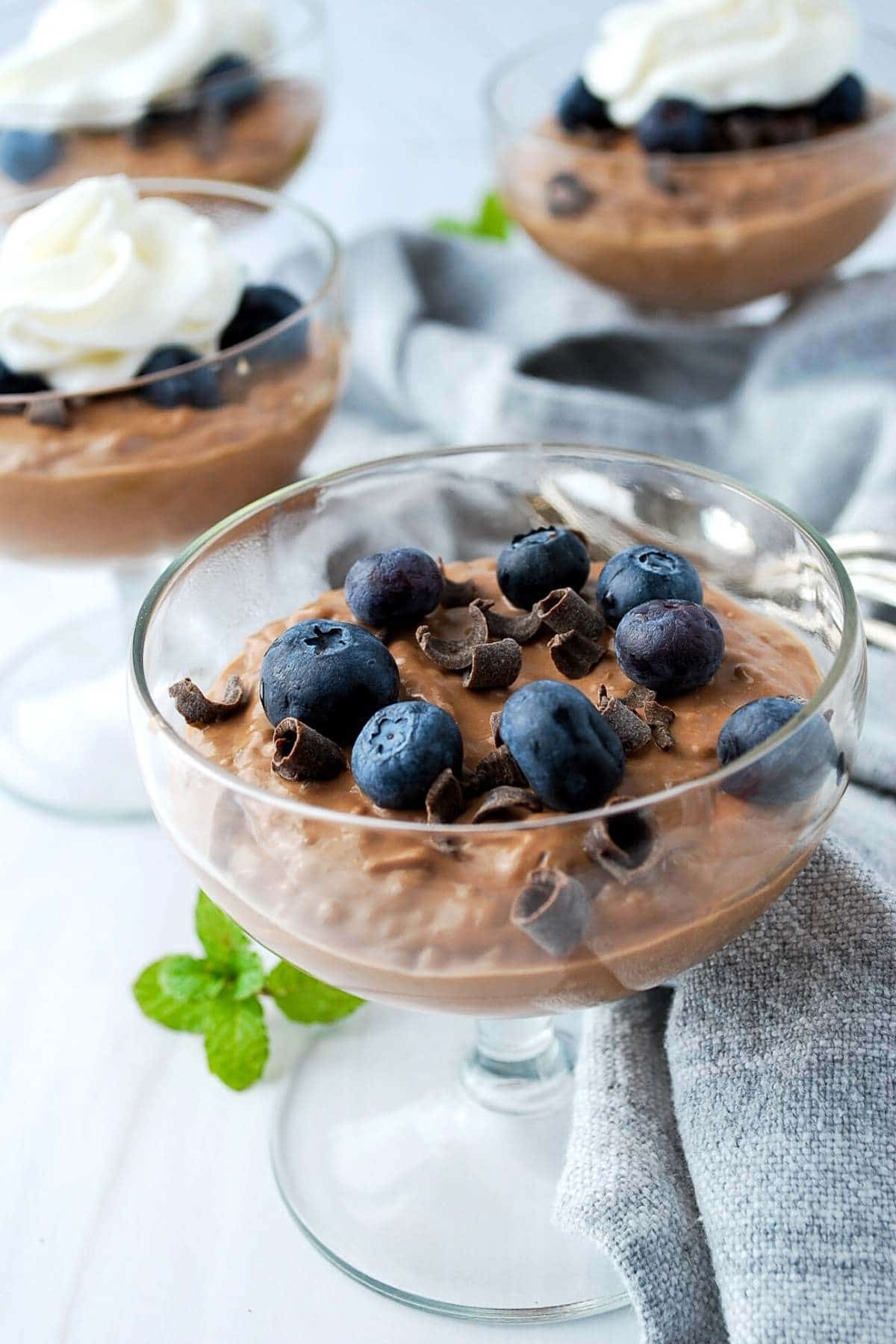 four dessert dishes with chocolate protein chia pudding with berries and whipped cream