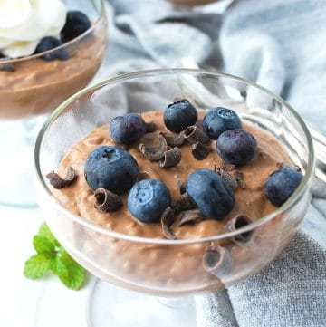 close up of chocolate chia seed pudding with fresh blueberries and chocolate on top