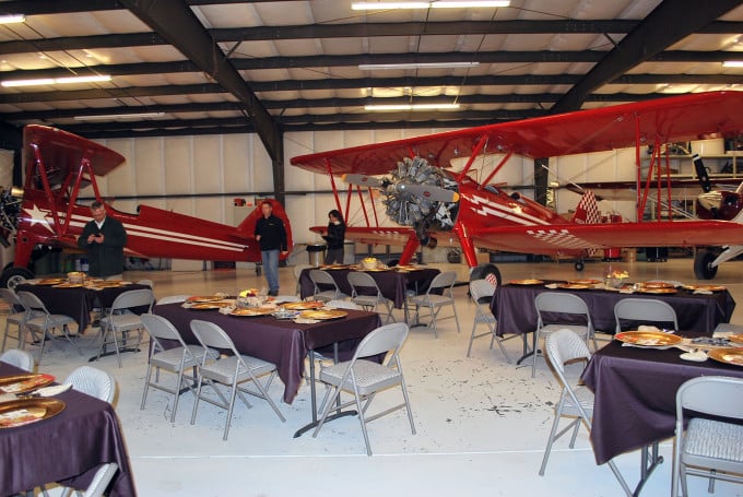A group of people sitting at a table at Hoff Farm in an airplane hangar