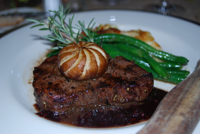 Steak on a plate with a mushroom garnish with cooked asparagus and a sprig of rosemary