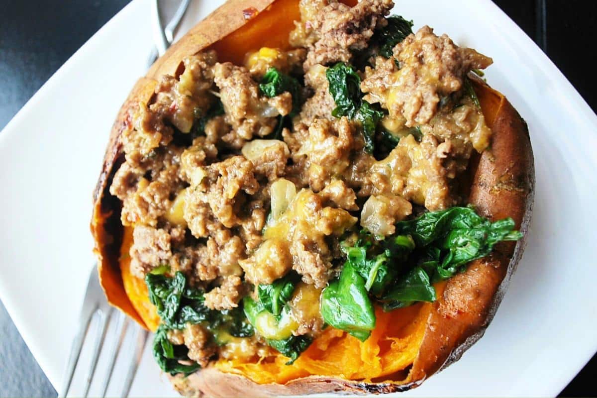 close up of a baked sweet potato filled with a cheesy beef sausage and kale stuffing