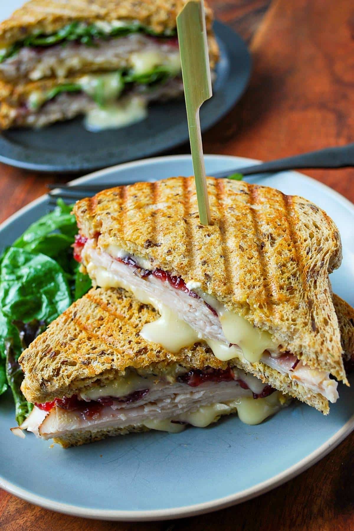 turkey cranberry brie sandwich on a plate with salad greens