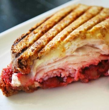 a close up photo of half of a turkey cranberry brie panini on a plate