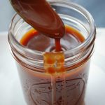 caramel sauce dripping off a spoon over a mason jar