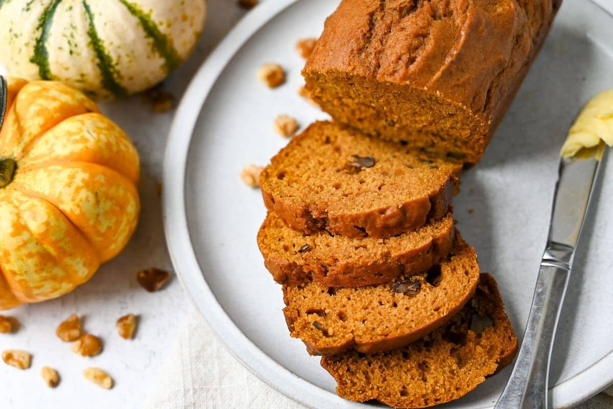 sliced pumpkin loaf with mini pie pumpkins next to it