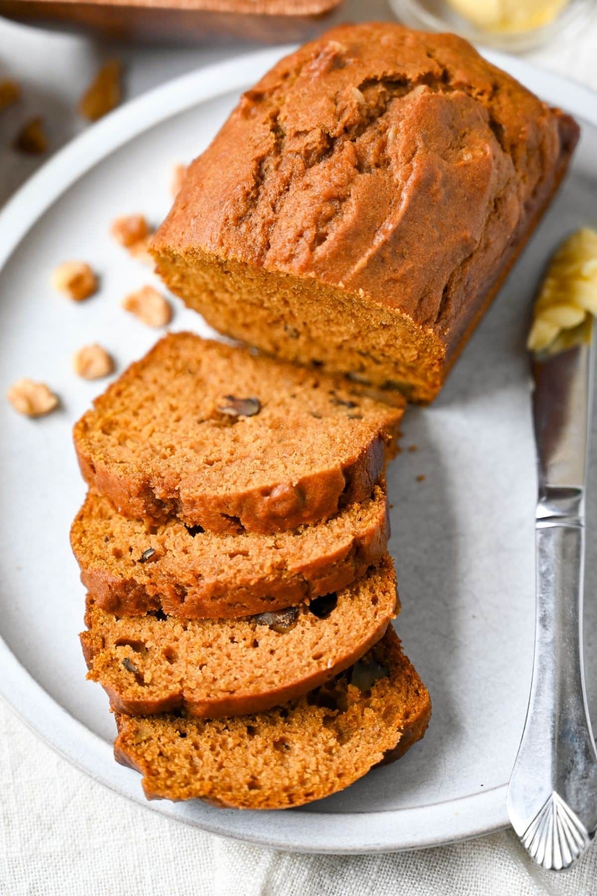 close up overhead shot of a sliced mini pumpkin walnut loaf with walnuts sprinkled around it