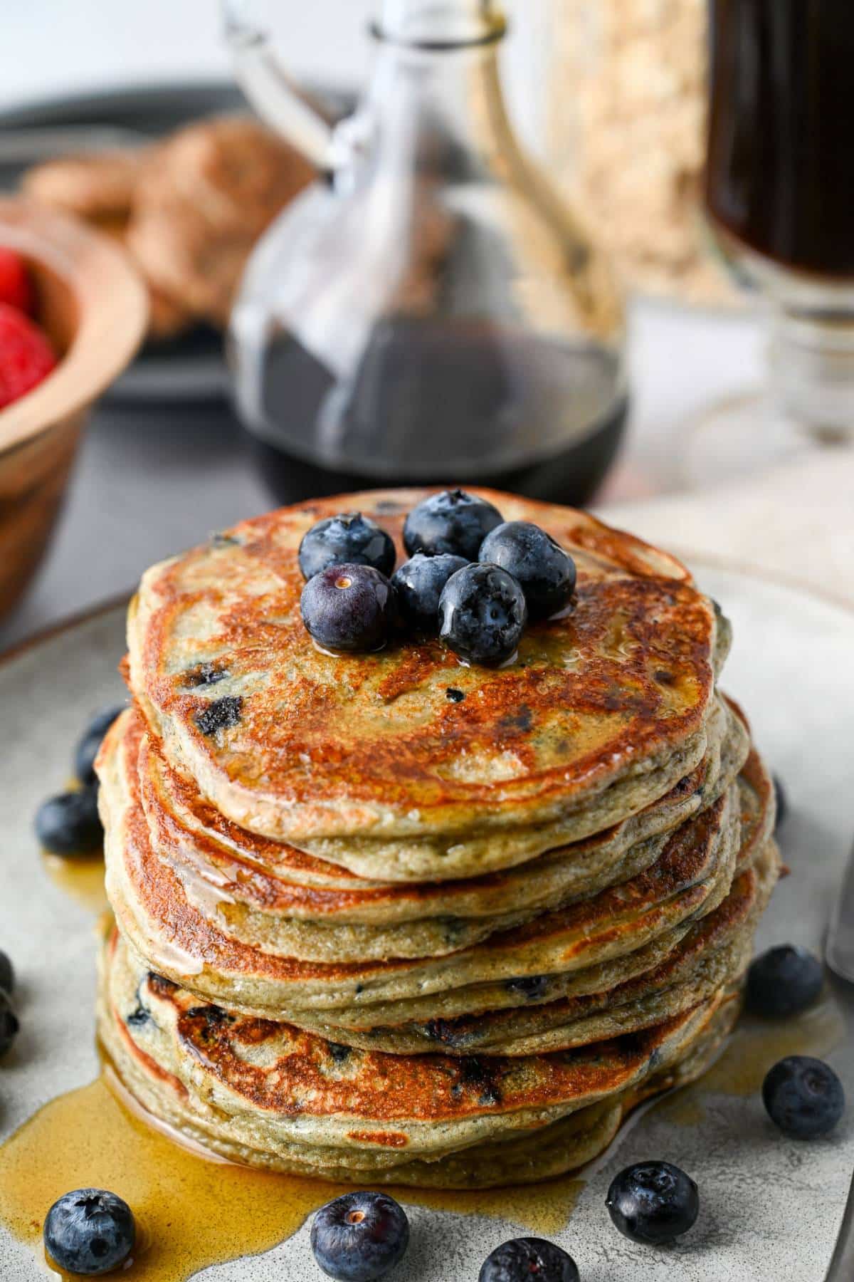 close up of a tall stack of blueberry pancakes made with oats and protein powder with syrup on top
