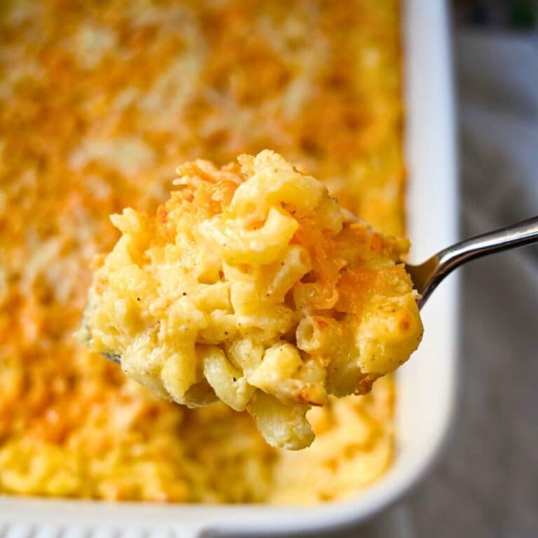 holding up a serving of mac and cheese over a casserole dish