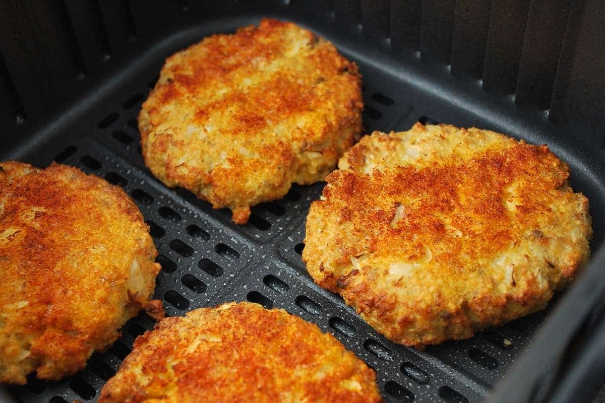 close up of cooked salmon patties in the air fryer  basket