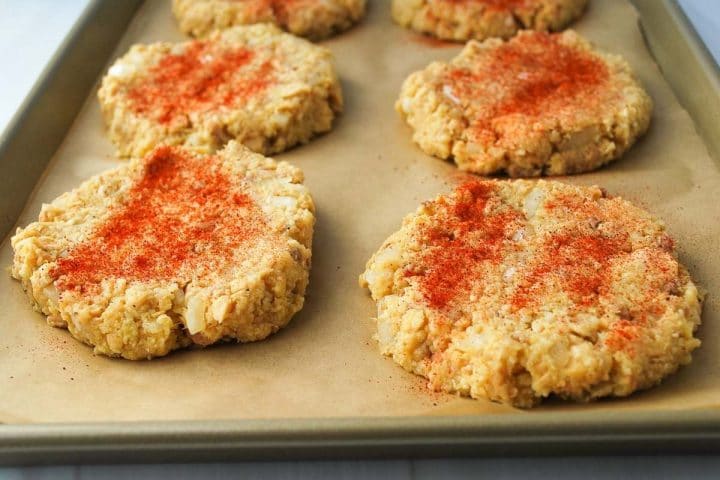 uncooked salmon patties on a parchment-lined baking sheet sprinkled with paprika 