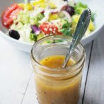 Greek dressing in a mason jar with salad in the background