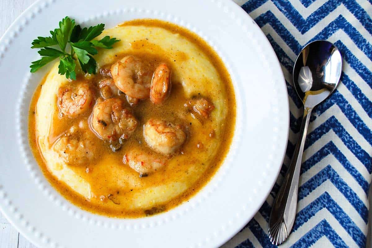 a bowl of shrimp and grits with a blue and white napkin and spoon