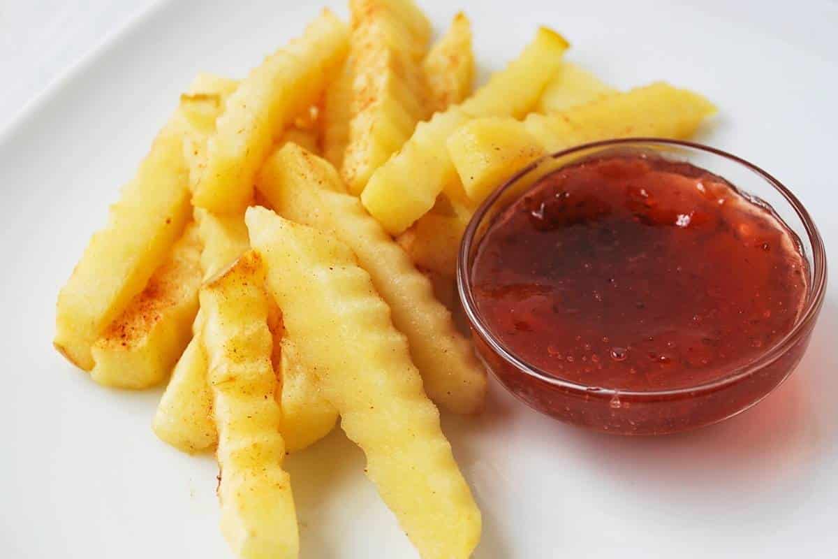 baked apple fries on a white plate with a dish of strawberry jam