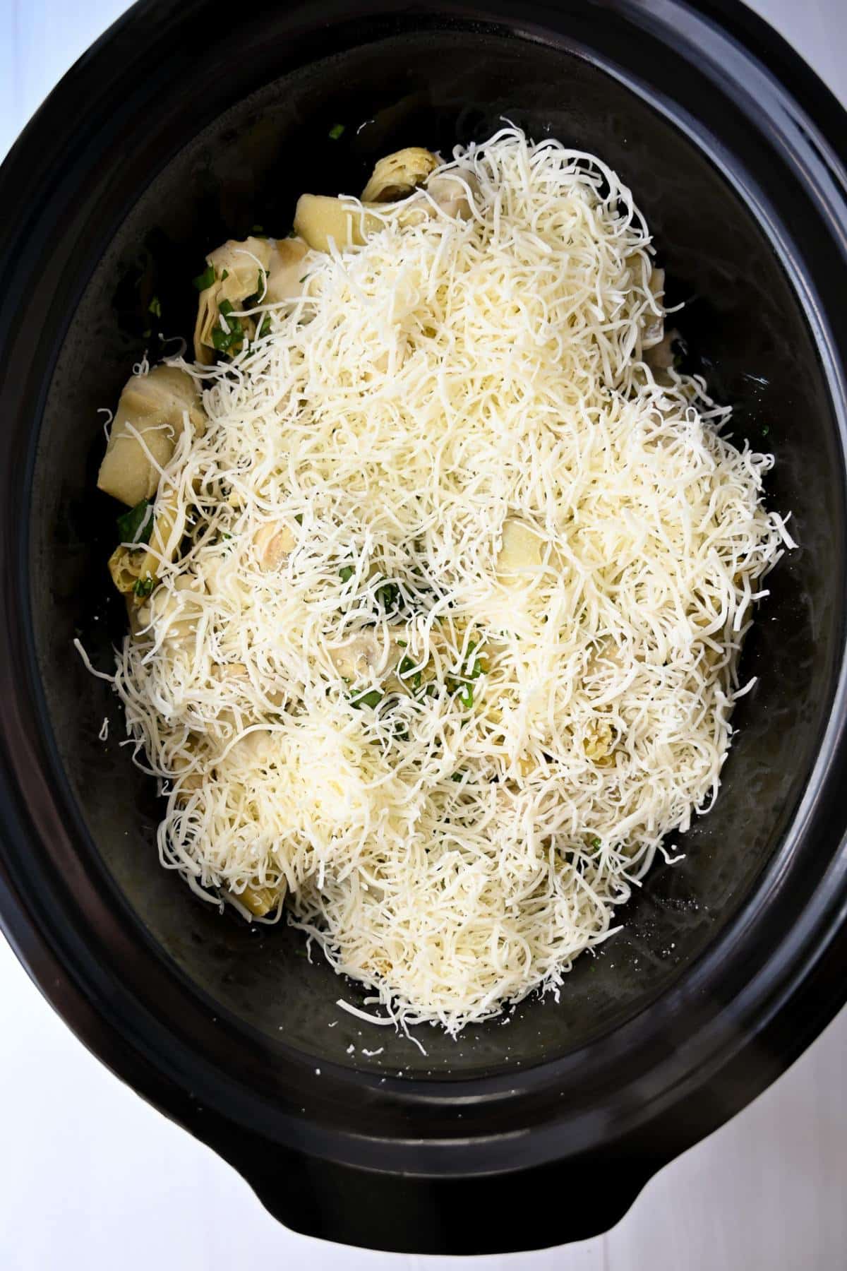 ingredients for making chicken with spinach and artichokes in a slow cooker ready to cook