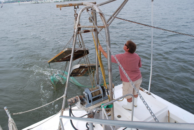 A man guiding a net on a shrimp boat