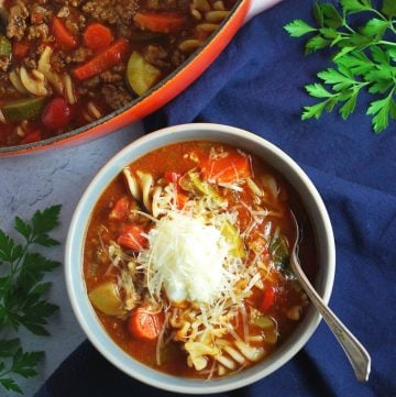 close up of bowl of lasagna soup with a spoon and blue napkin
