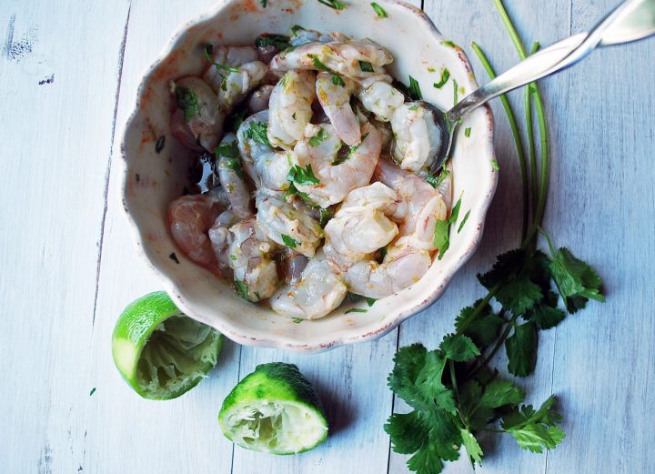 shrimp marinating in bowl with herbs and lime