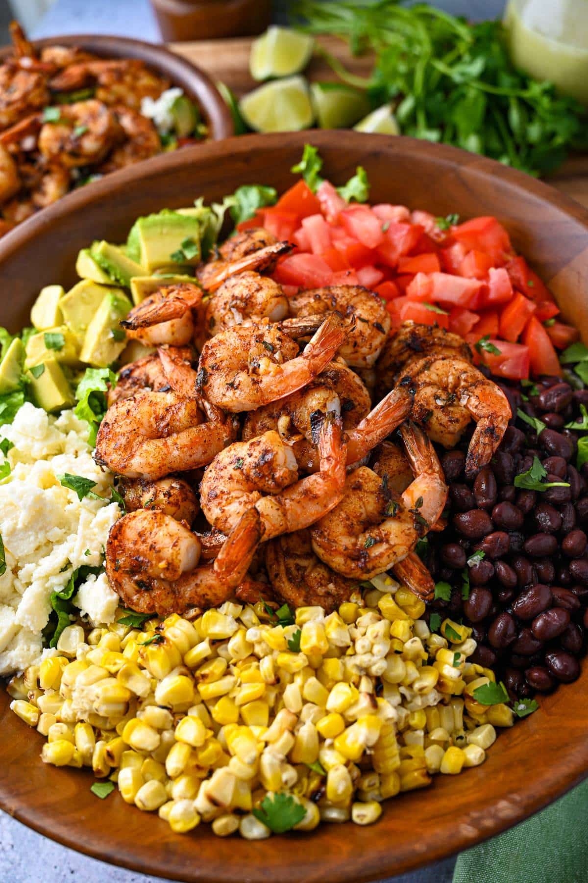 close up of a large wooden bowl with grilled shrimp salad with mexican inspired ingredients