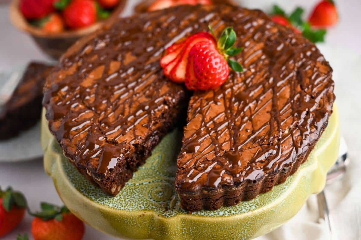 side view of a sliced brownie pie tart with a fresh strawberry