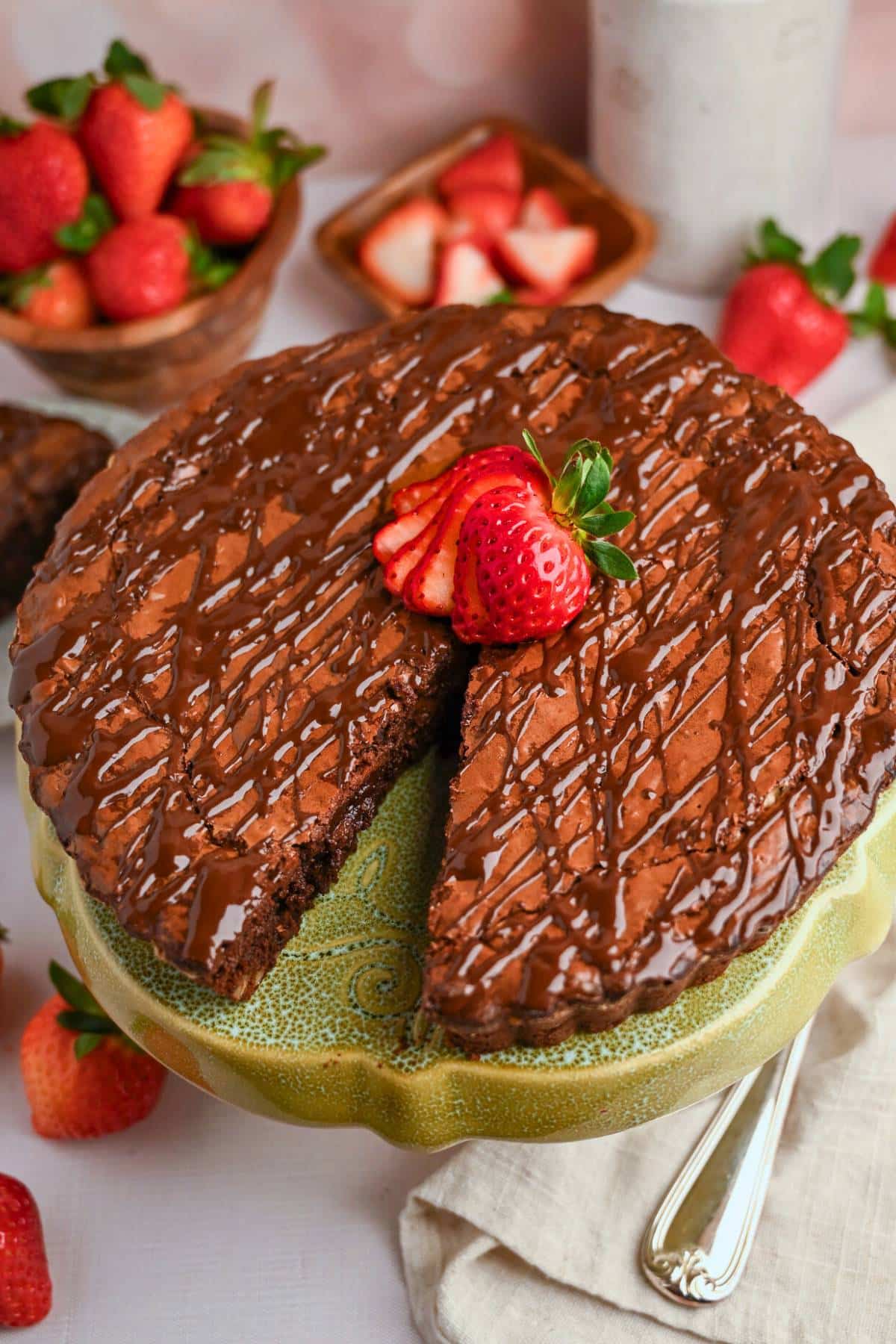 sliced brownie tart with a strawberry on top with strawberries all around it
