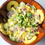 close up of cuban avocado salad with slices of fresh pineapple in a wood salad bowl