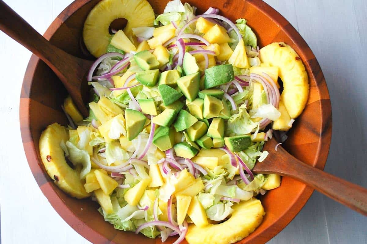 overhead photo of cuban avocado salad in a wooden salad bowl with serving spoons