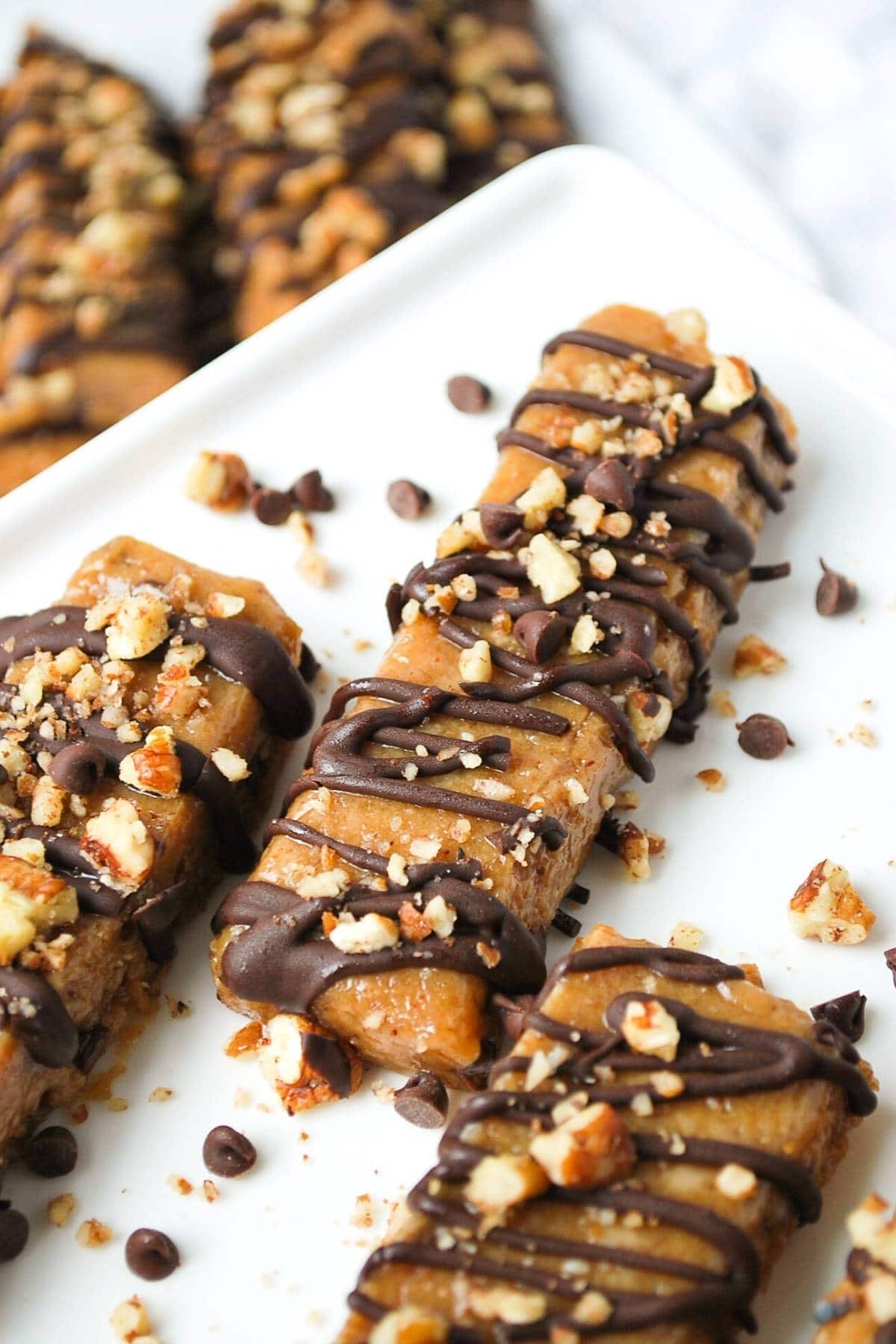 no bake gluten free protein bars on a platter drizzled in chocolate and sprinkled with nuts