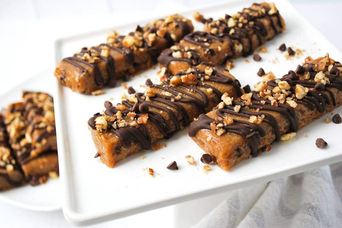 no bake peanut butter protein bars on a platter drizzled in chocolate and sprinkled with nuts