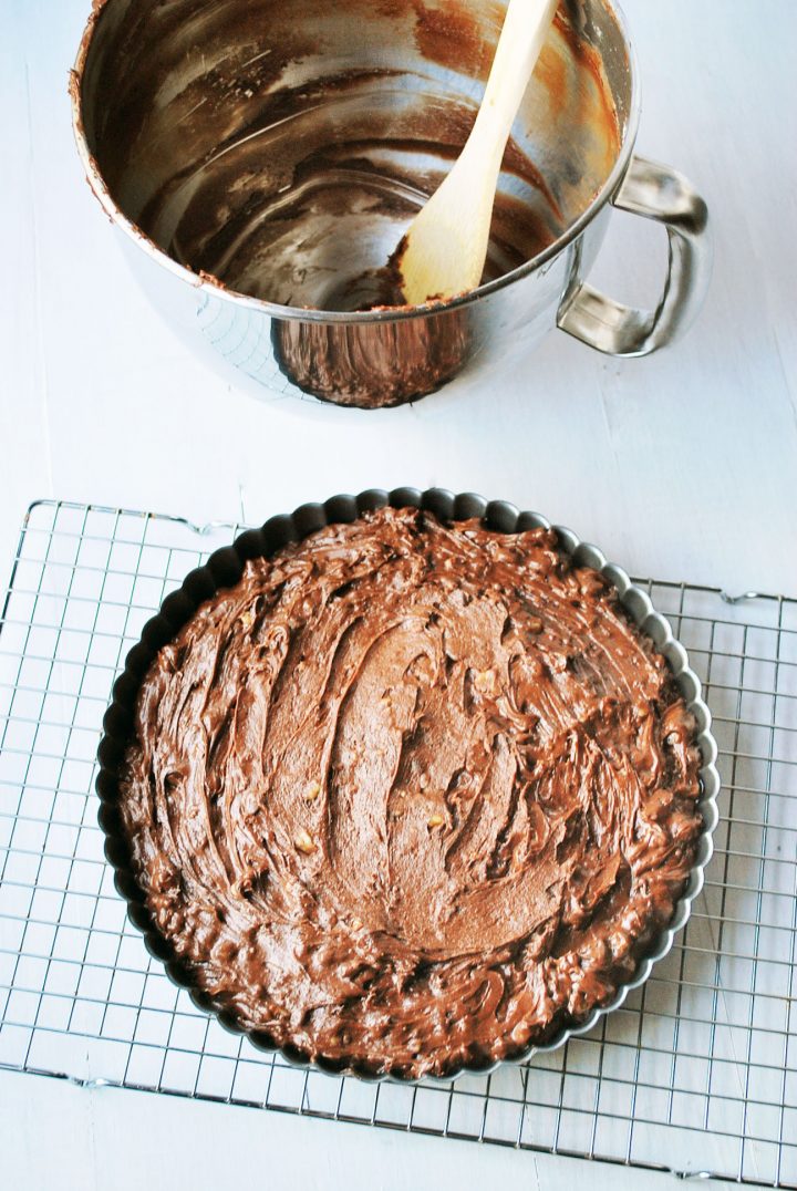 brownie batter in tart pan ready to bake with empty bowl and spoon