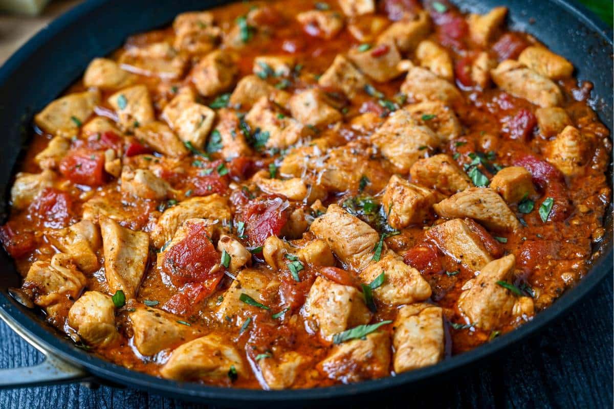 a tomato chicken skillet with fresh basil sprinkled on top