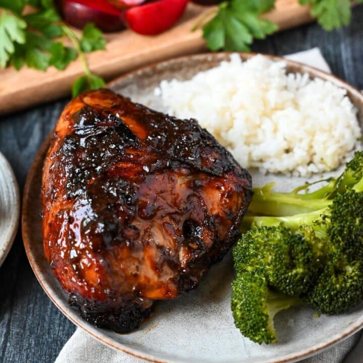 a piece of bone-in BBQ grilled chicken on a plate with rice and broccoli