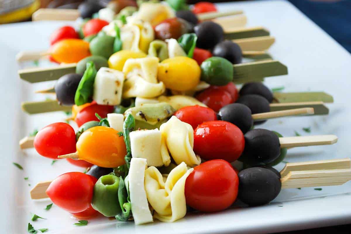 side view of caprese tortellini skewers with fresh parsley sprinkled on the tray