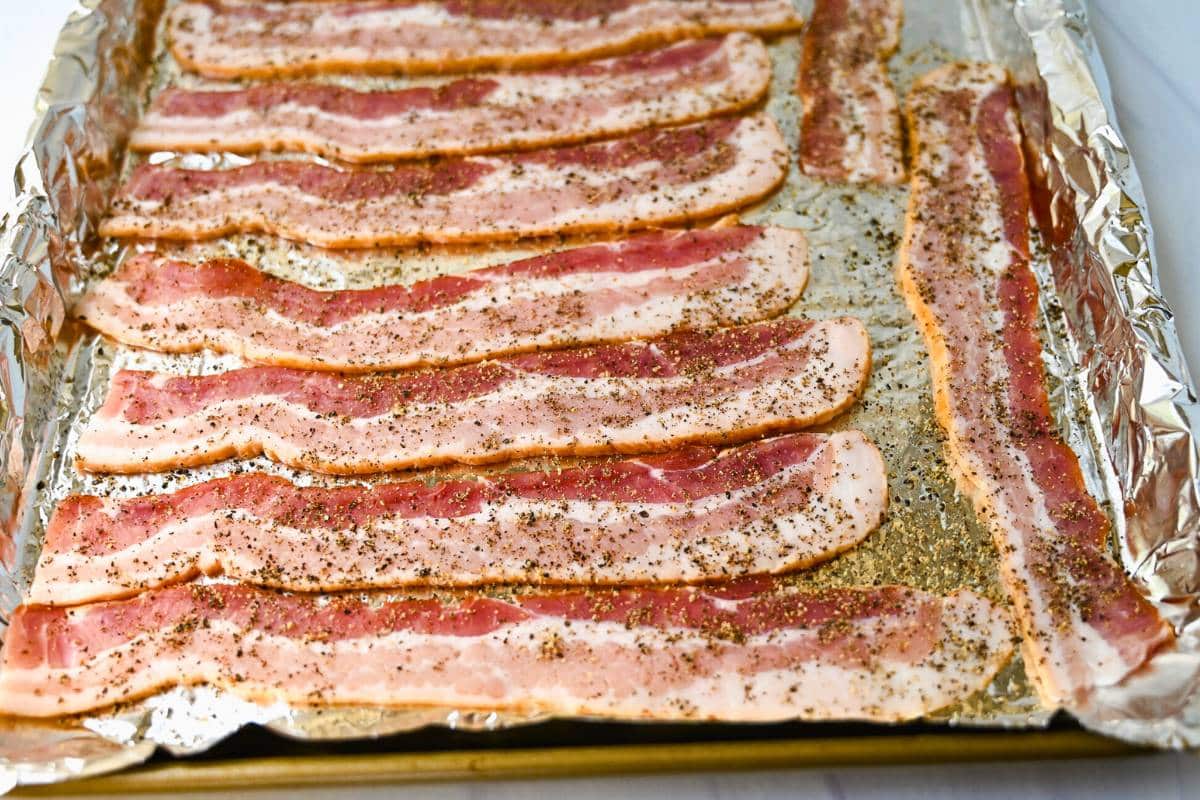peppered bacon on a foil-lined baking sheet
