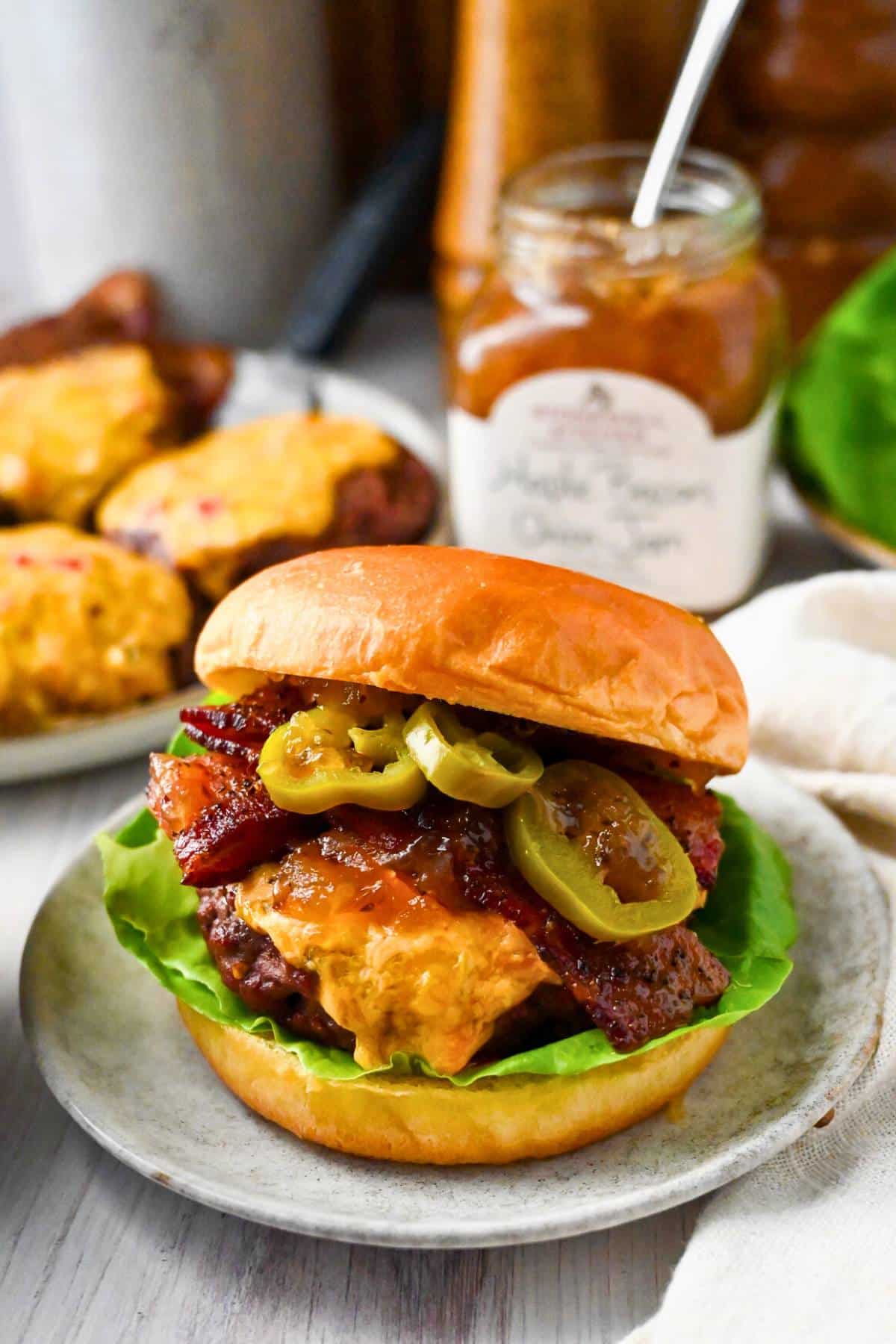 a pimento cheese burger with a plate of burgers with melted pimento cheese and a jar of jam