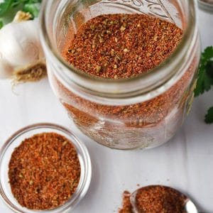overhead photo of homemade taco seasoning in a mason jar with a small dish of seasoning next to it
