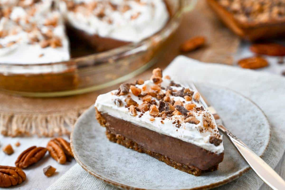 a slice of chocolate cream pie with a sliced pie in the background