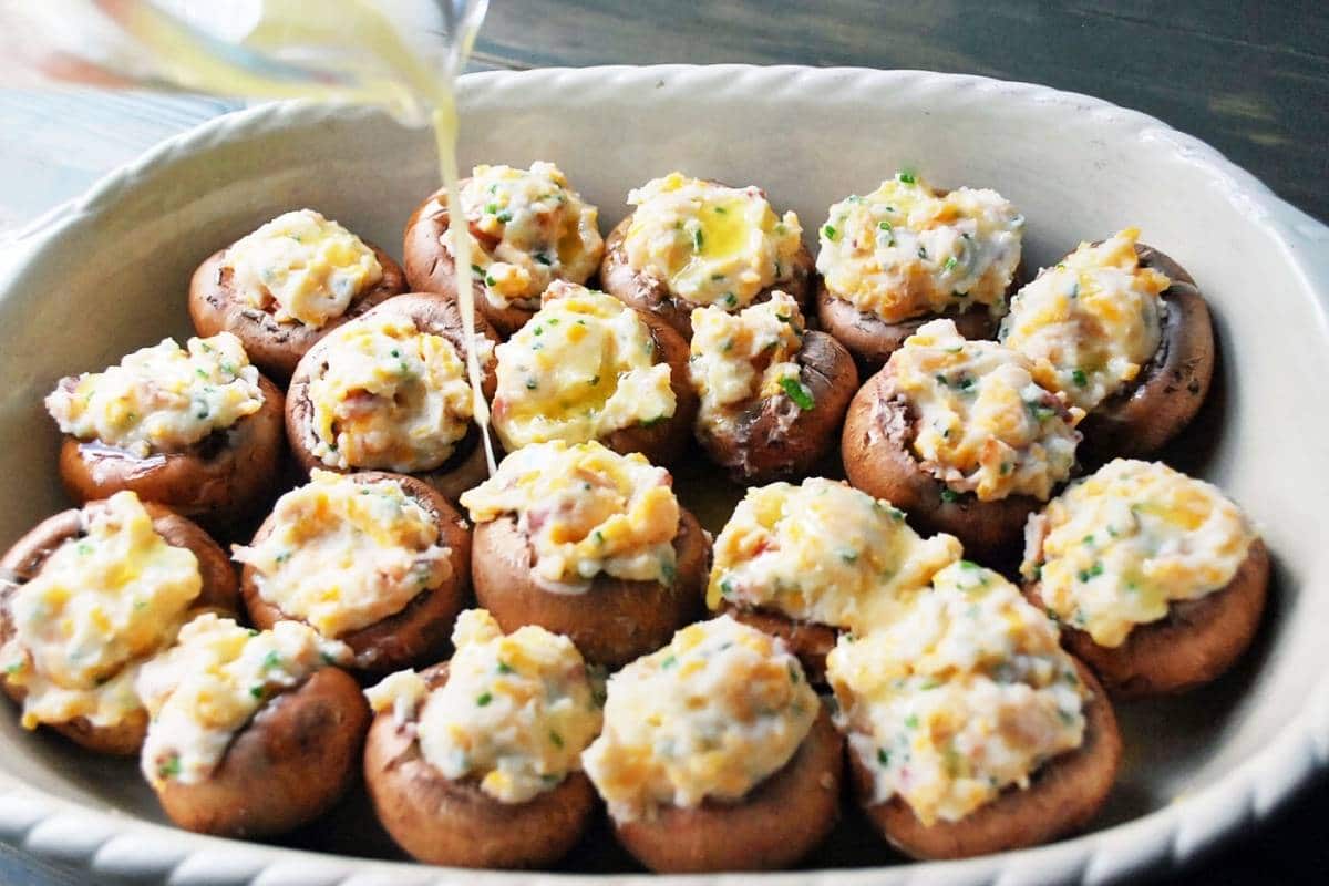 drizzling butter over gluten free stuffed mushrooms with loaded potato filling