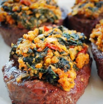 steaks on a plate topped with a feta spinach topping