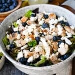 a serving bowl of salad with feta, blueberries and chicken