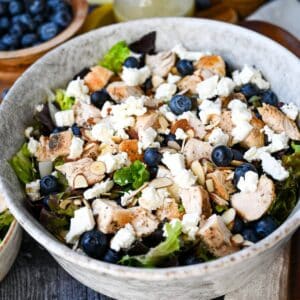 a serving bowl of salad with feta, blueberries and chicken
