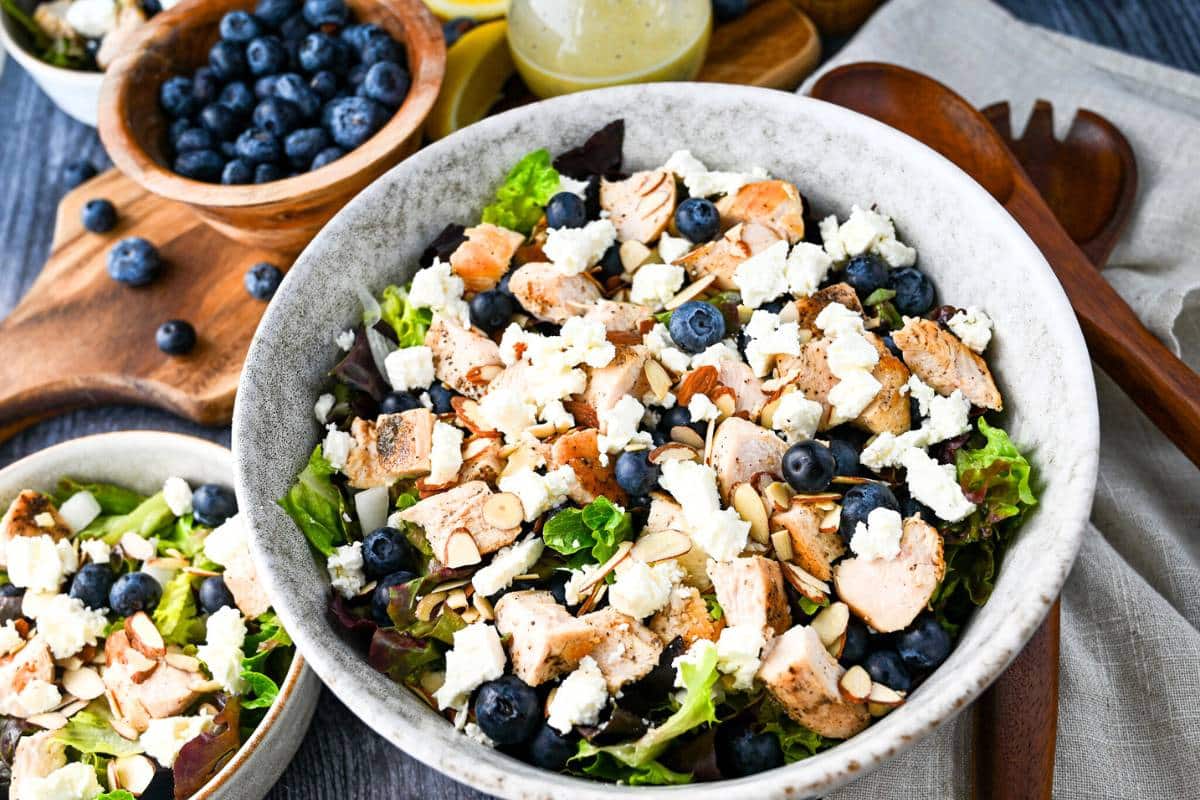 chopped summer salad in bowls with a bowl of blueberries next to it