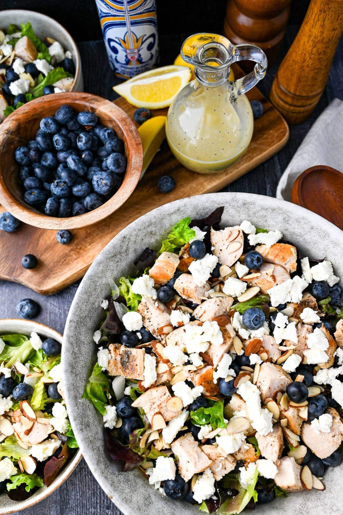 overhead photo of a large bowl of chopped salad with a bowl of blueberries and a jar of homemade lemon poppyseed dressing