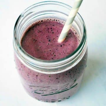 blueberry kale smoothie in a mason jar glass with a straw