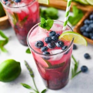 close up of a blueberry mojito in a tall glass