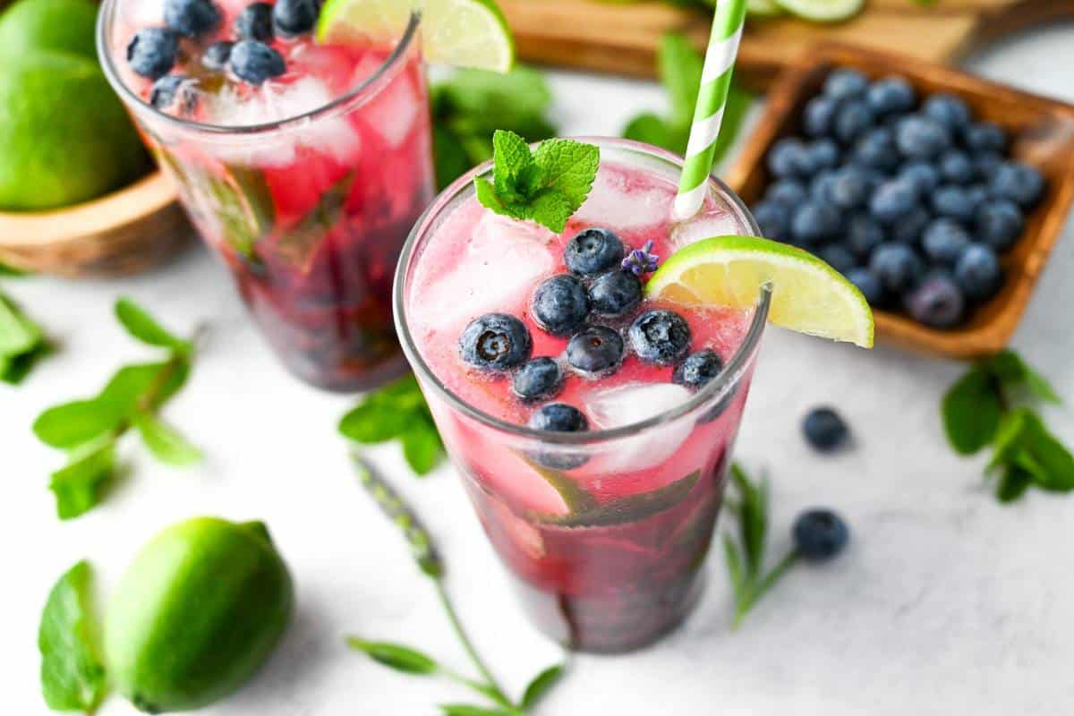 two mojitos with fresh lime, blueberries, mint and lavender