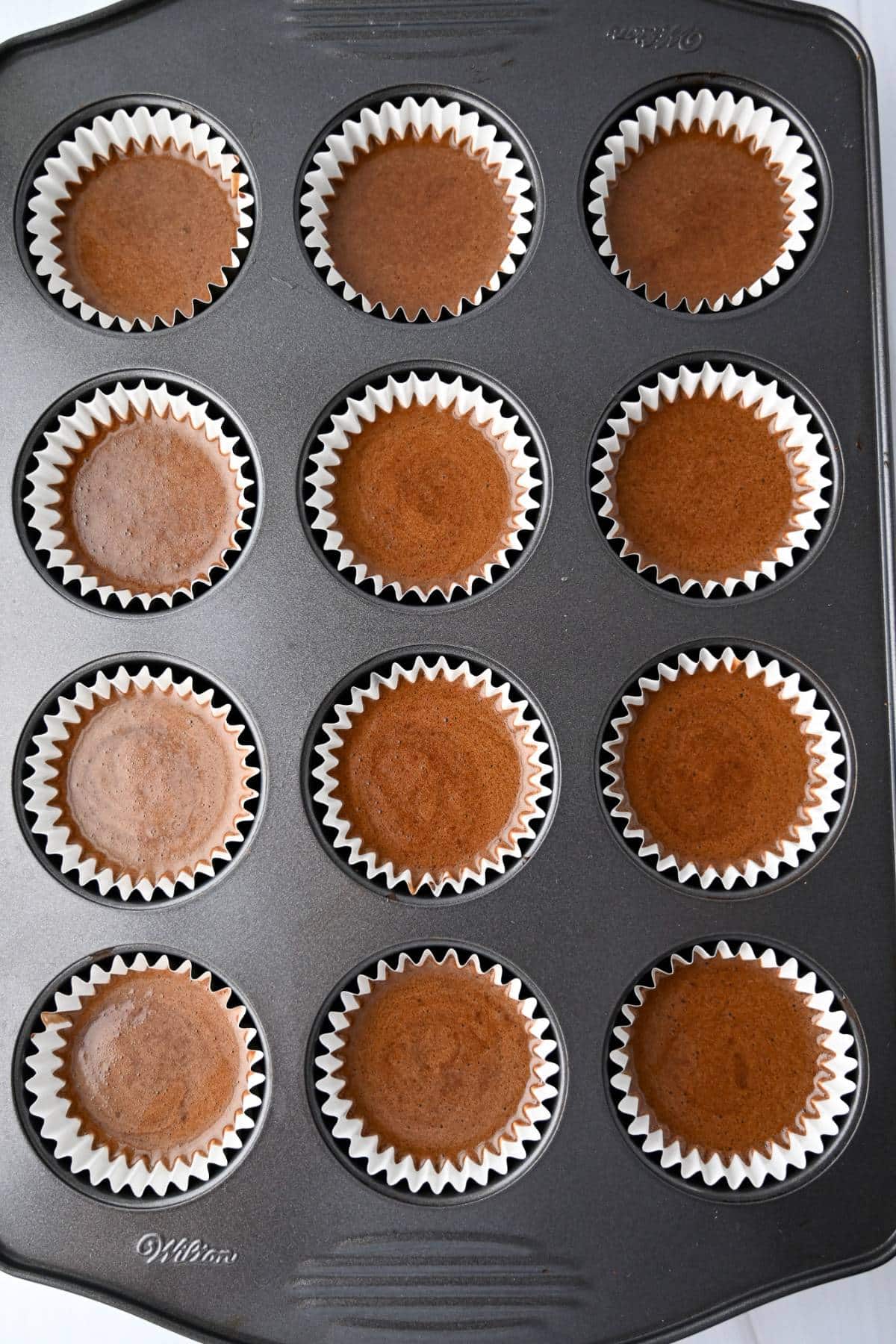chocolate cupcake batter in liners in a muffin tin