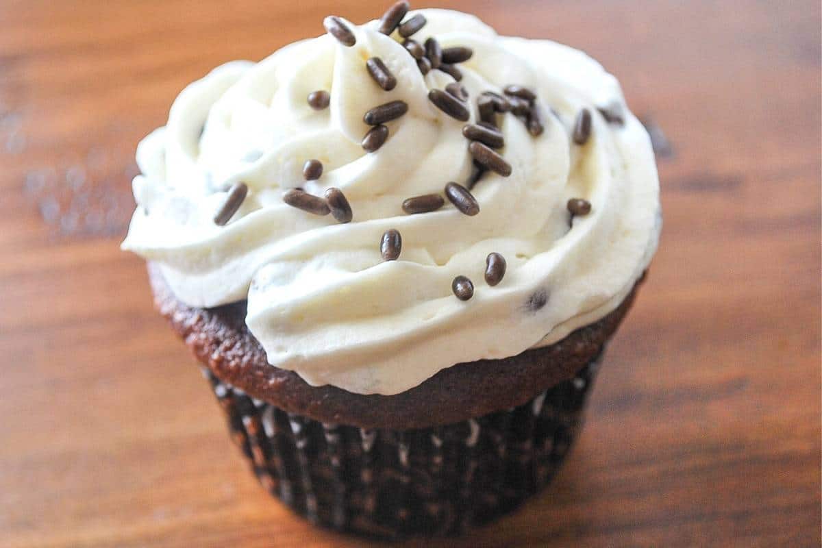 a single devil's food chocolate cupcake with chocolate chip buttercream on a wood counter