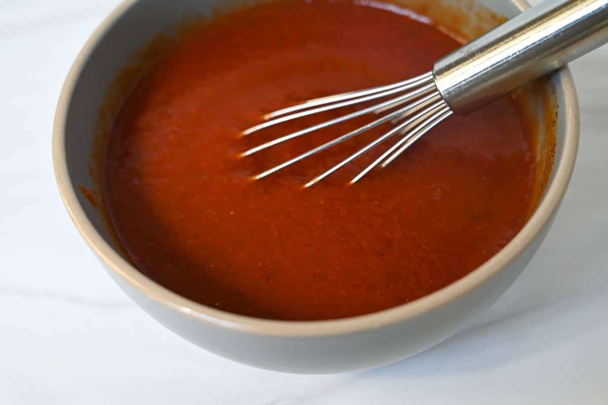 red sauce for stuffed collards in a bowl with a whisk